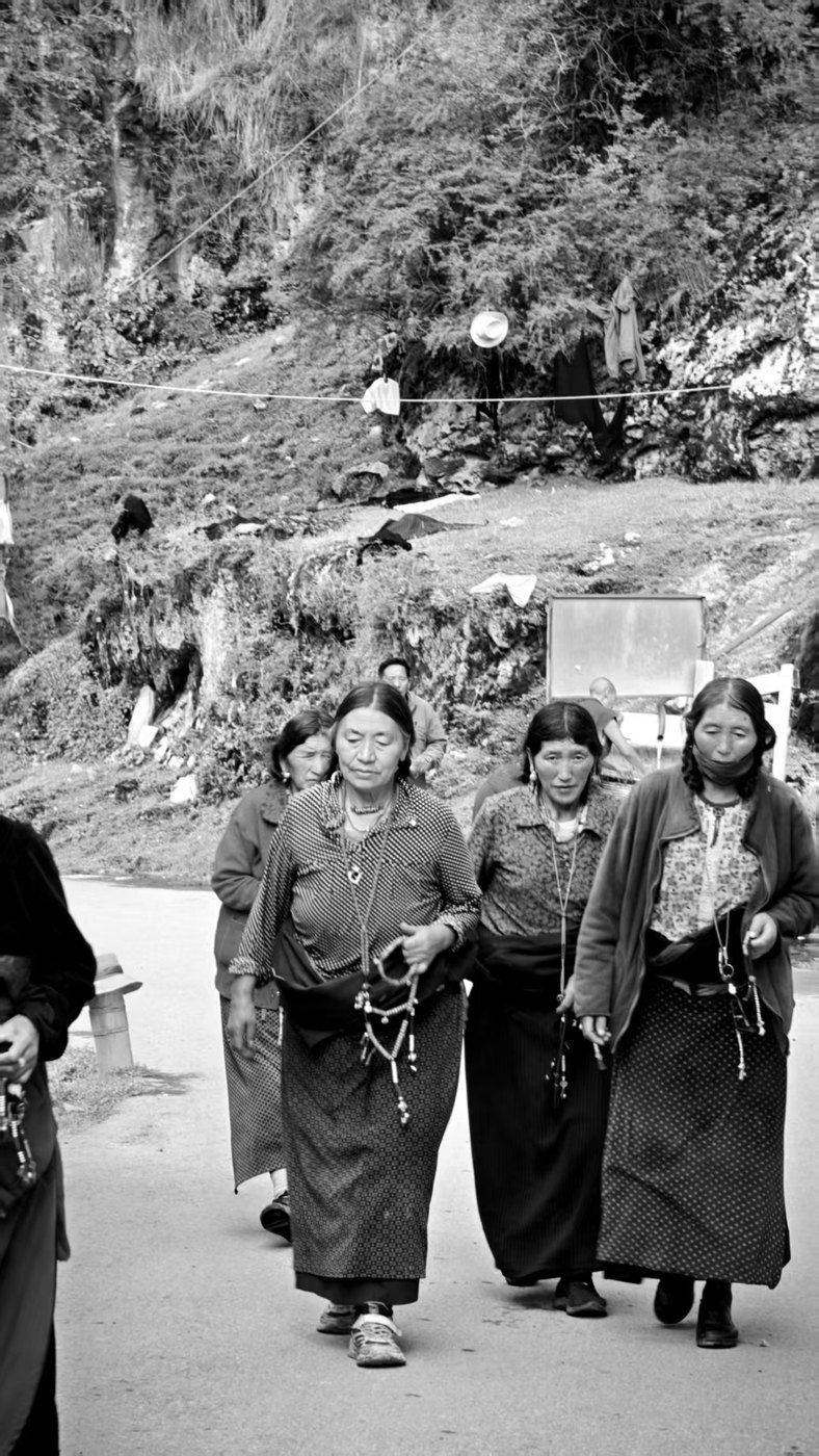 黑白:几位手持念珠的妇女并肩走在山路上