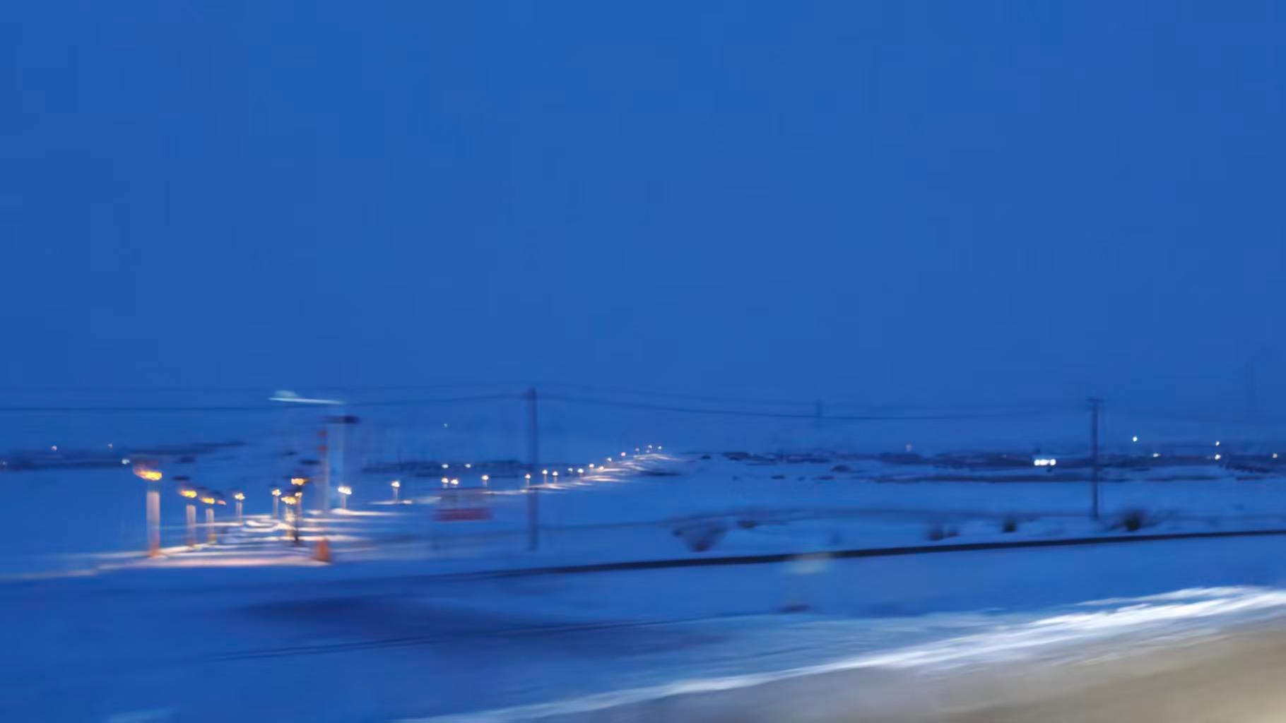 蓝调时分,雪原上的路灯连成一线